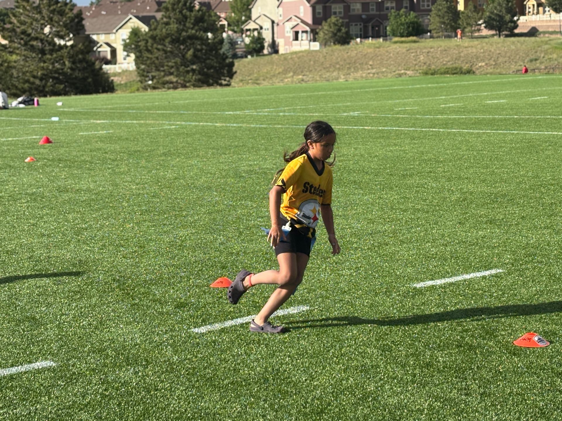 Young athlete in a yellow jersey running on a grassy field during a sports practice.