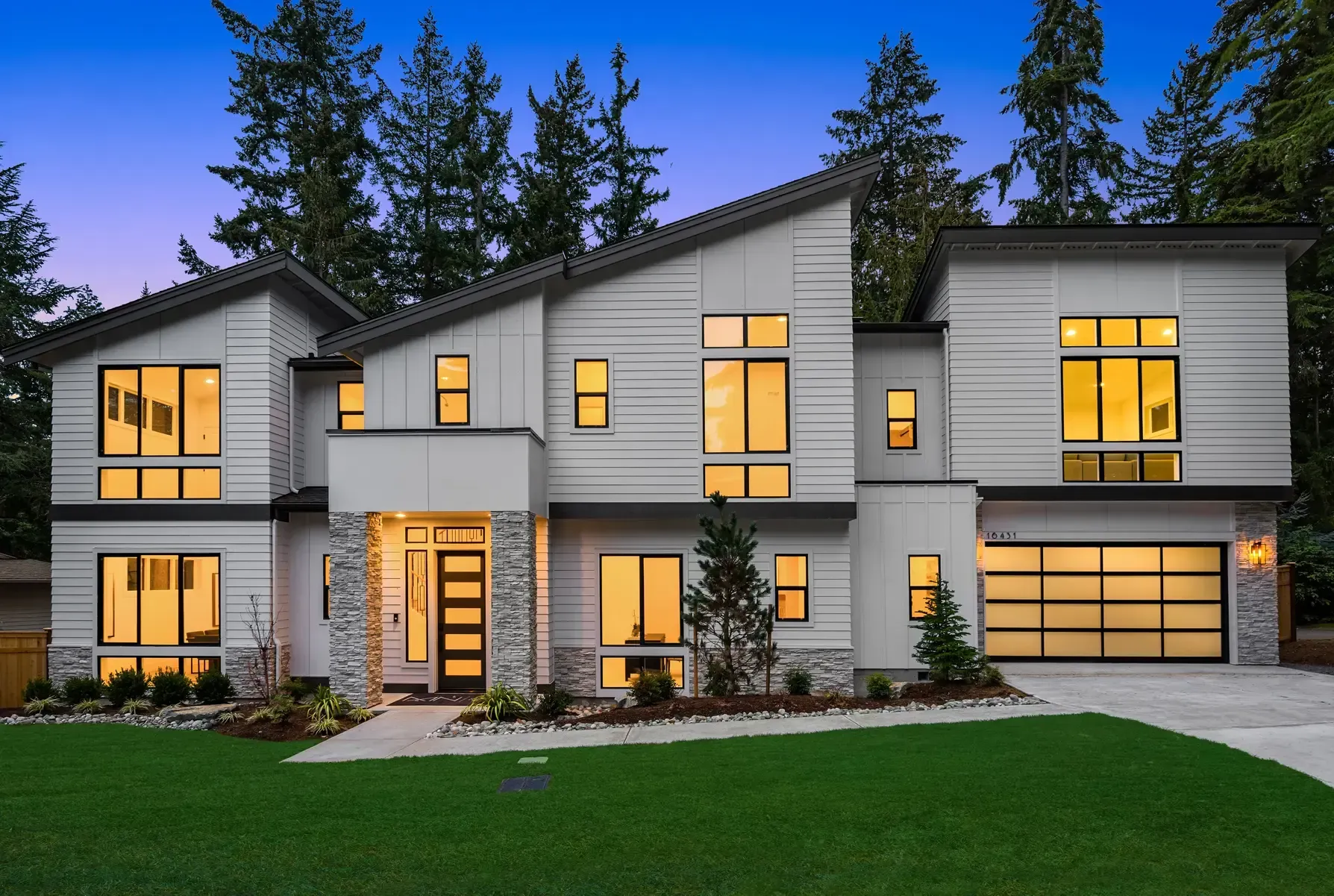 A large modern house with a lot of windows and a garage.