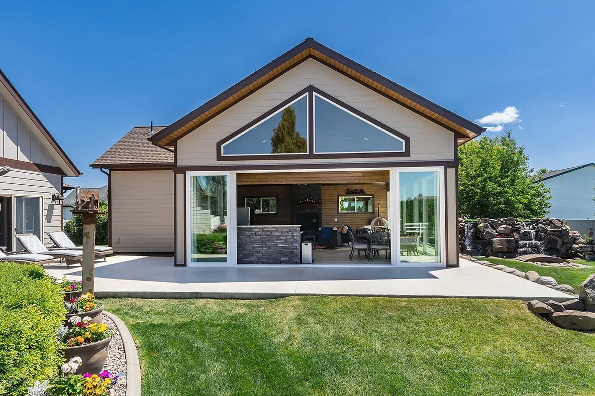 A house with a lot of windows and a patio in front of it.