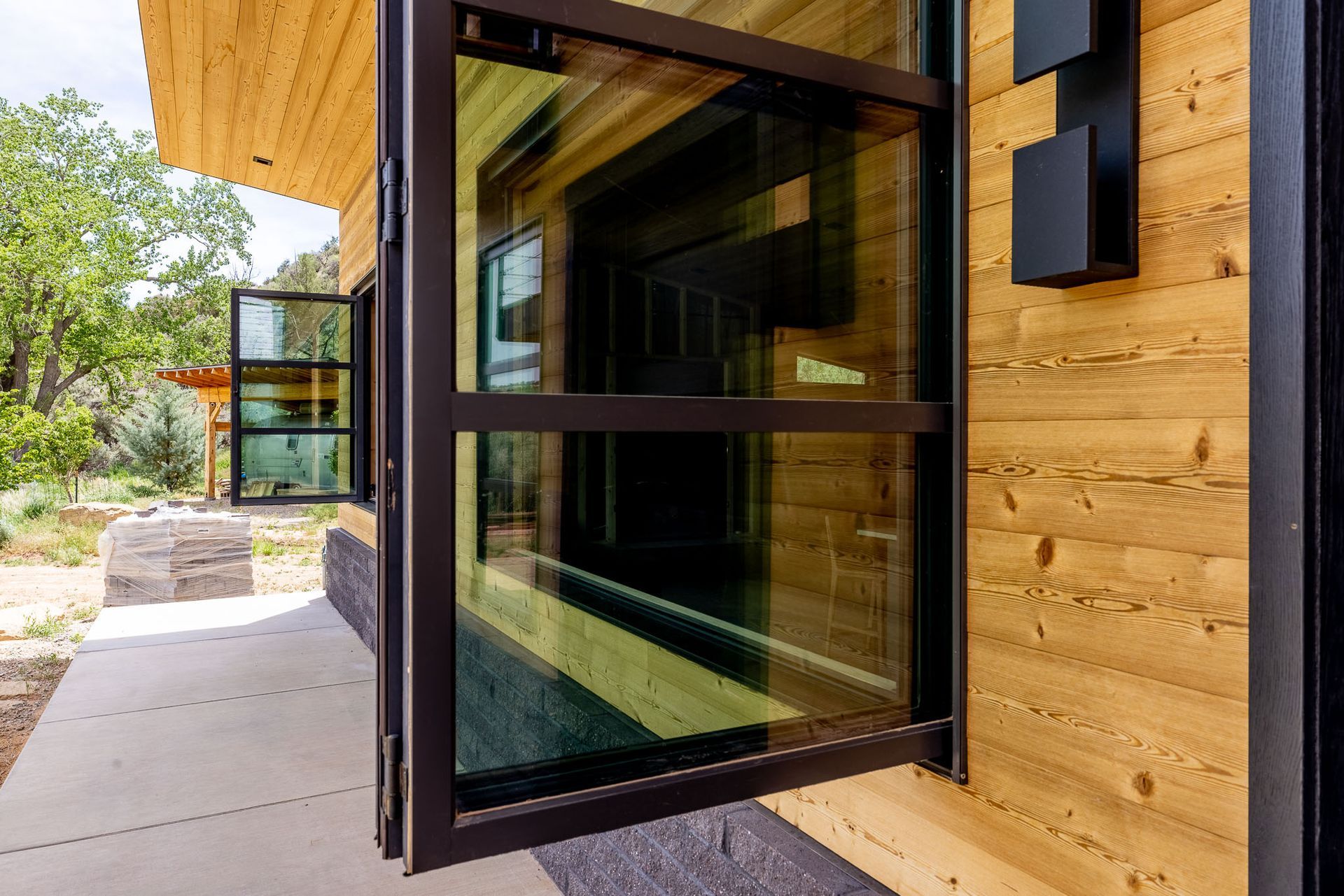 A large glass door is open to a wooden house.