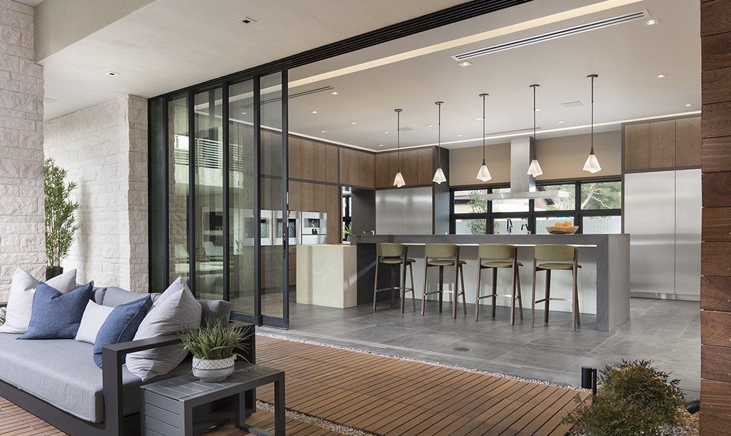 A living room with a couch and a table and a kitchen with sliding glass doors.