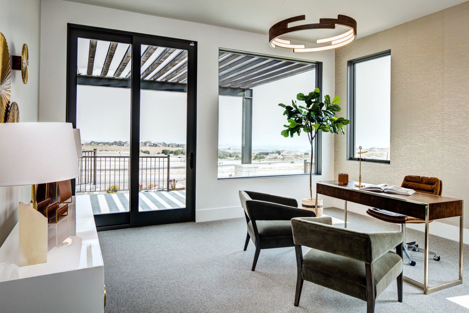 A home office with a desk , chairs and a large window.