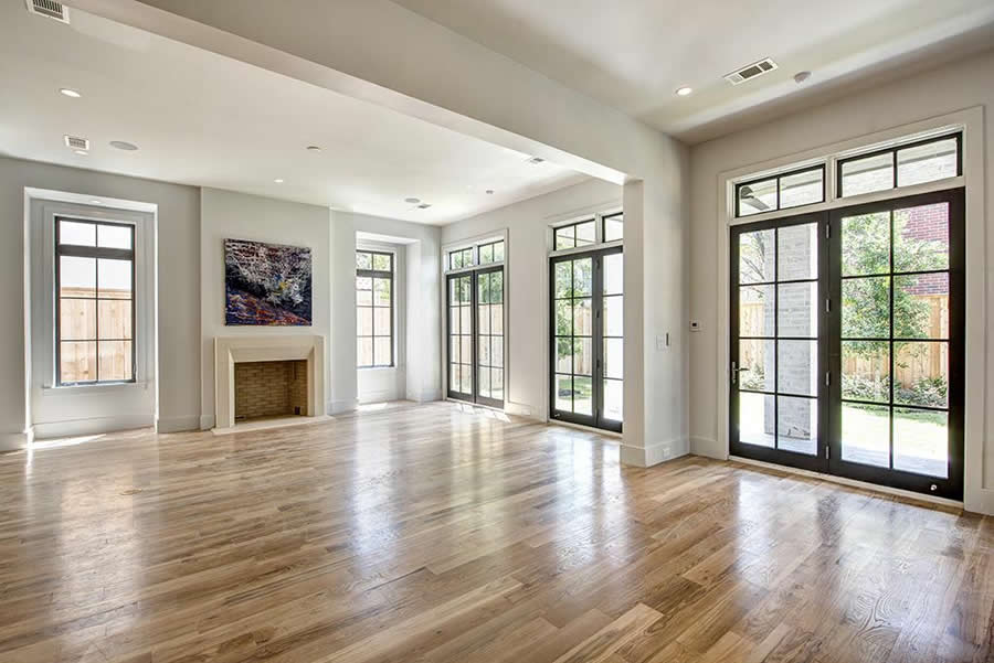 An empty living room with hardwood floors , a fireplace , and lots of windows.