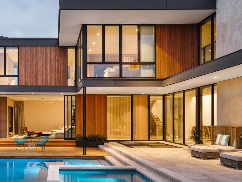 A modern house with a large swimming pool in front of it.