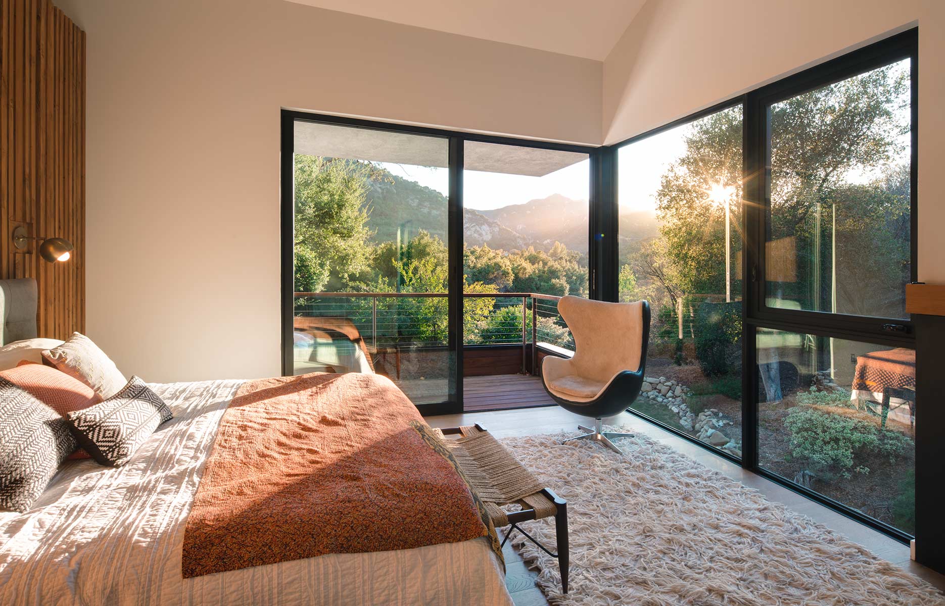 A bedroom with a large bed , chair and sliding glass doors.