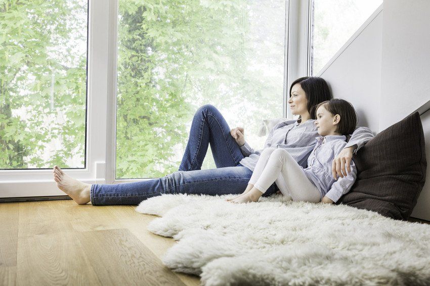A woman and a child are sitting on the floor in front of a window.