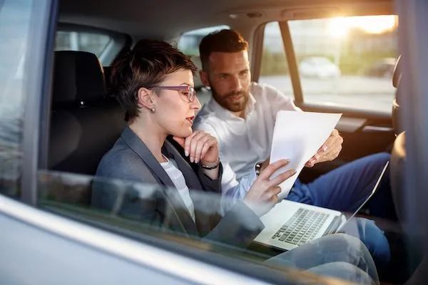 A man is helping a woman get out of a car.