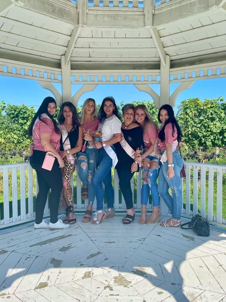 East End Wine Tasting Tour's Bachelorette Group posing in the Pellegrini Vineyard Pergola