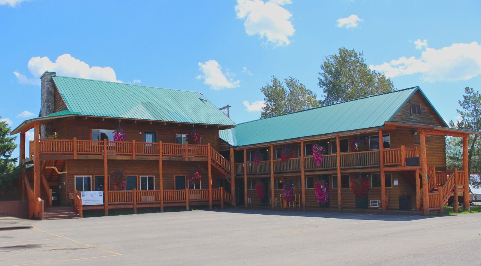 Log cabin motel with green roof and wooden balconies under a blue sky.