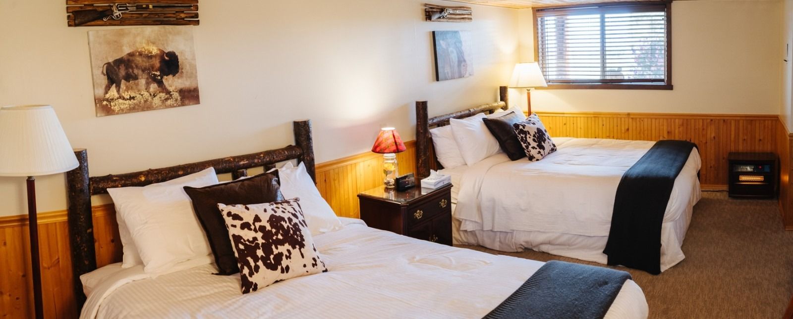 Bedroom with two beds, wood-framed headboards, white bedding, decorative pillows, and a window.