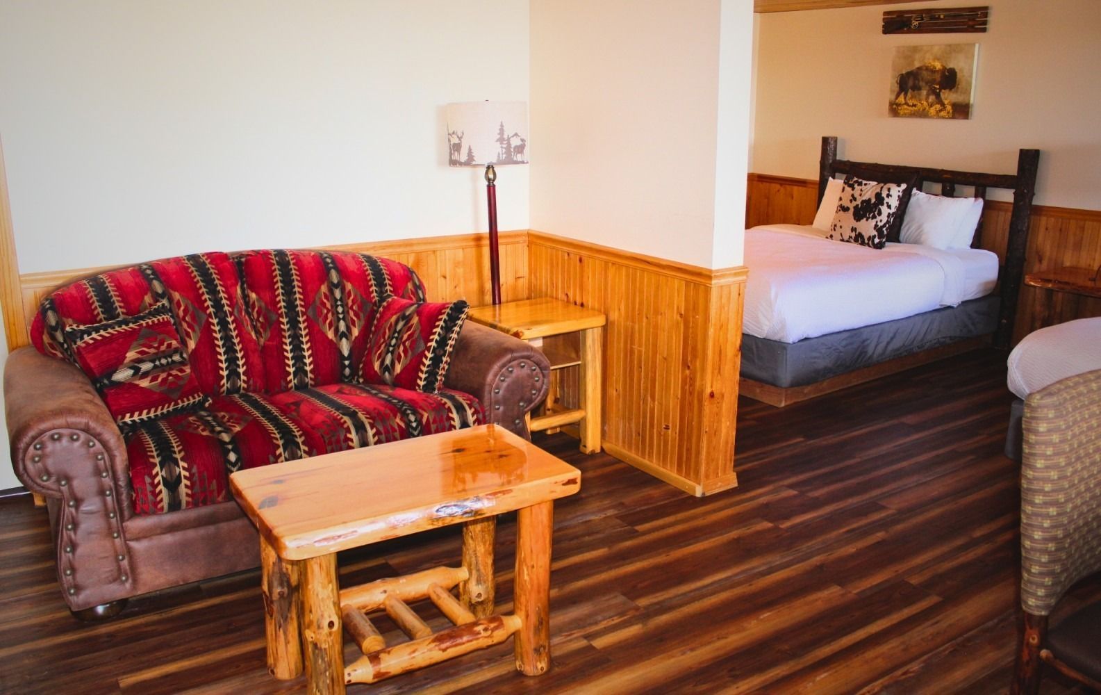 Cozy hotel room with a red sofa, wooden furniture, and a bed in the background.