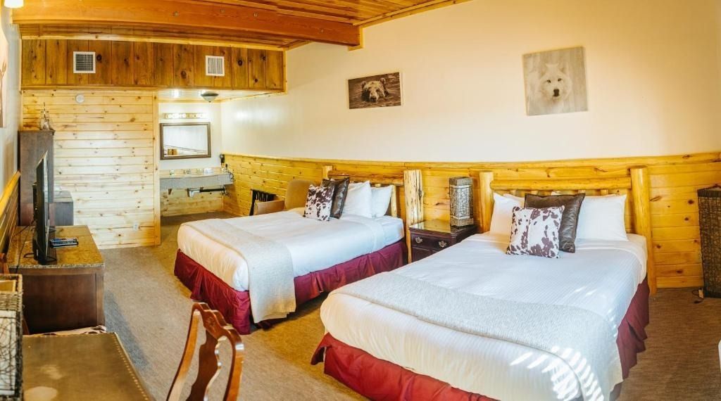 Hotel room with two beds, wood paneling, and a TV.