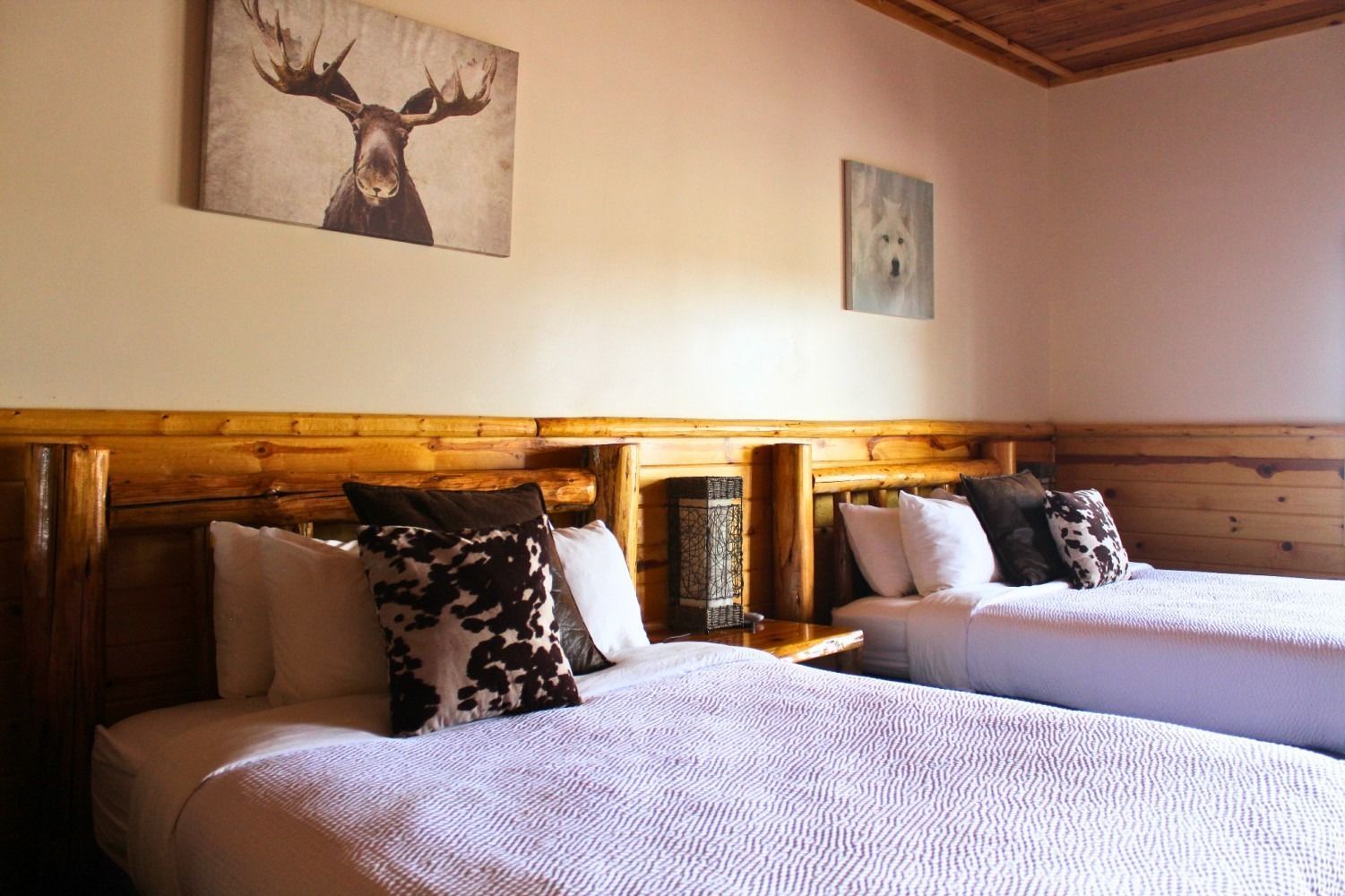 Two twin beds with white bedding in a room, decorated with animal art and wood accents.