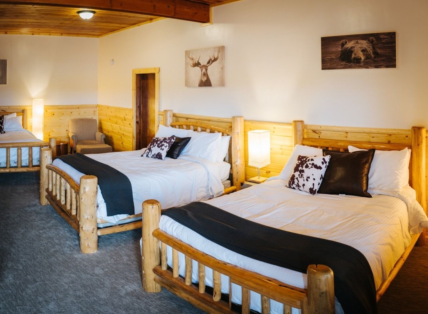 A hotel room with three beds, wooden frames, and rustic decor.