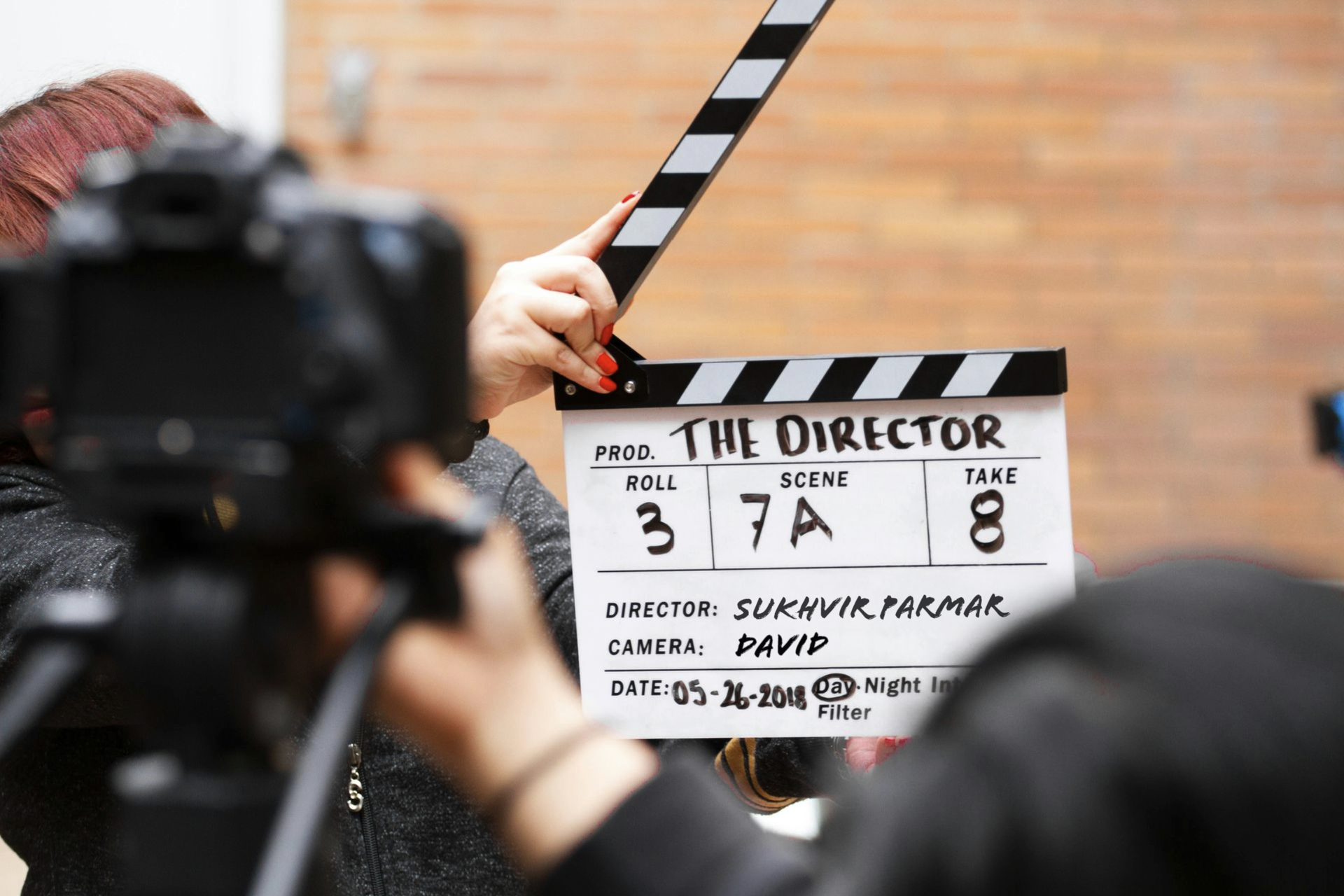 A person is holding a clapper board that says the director on it