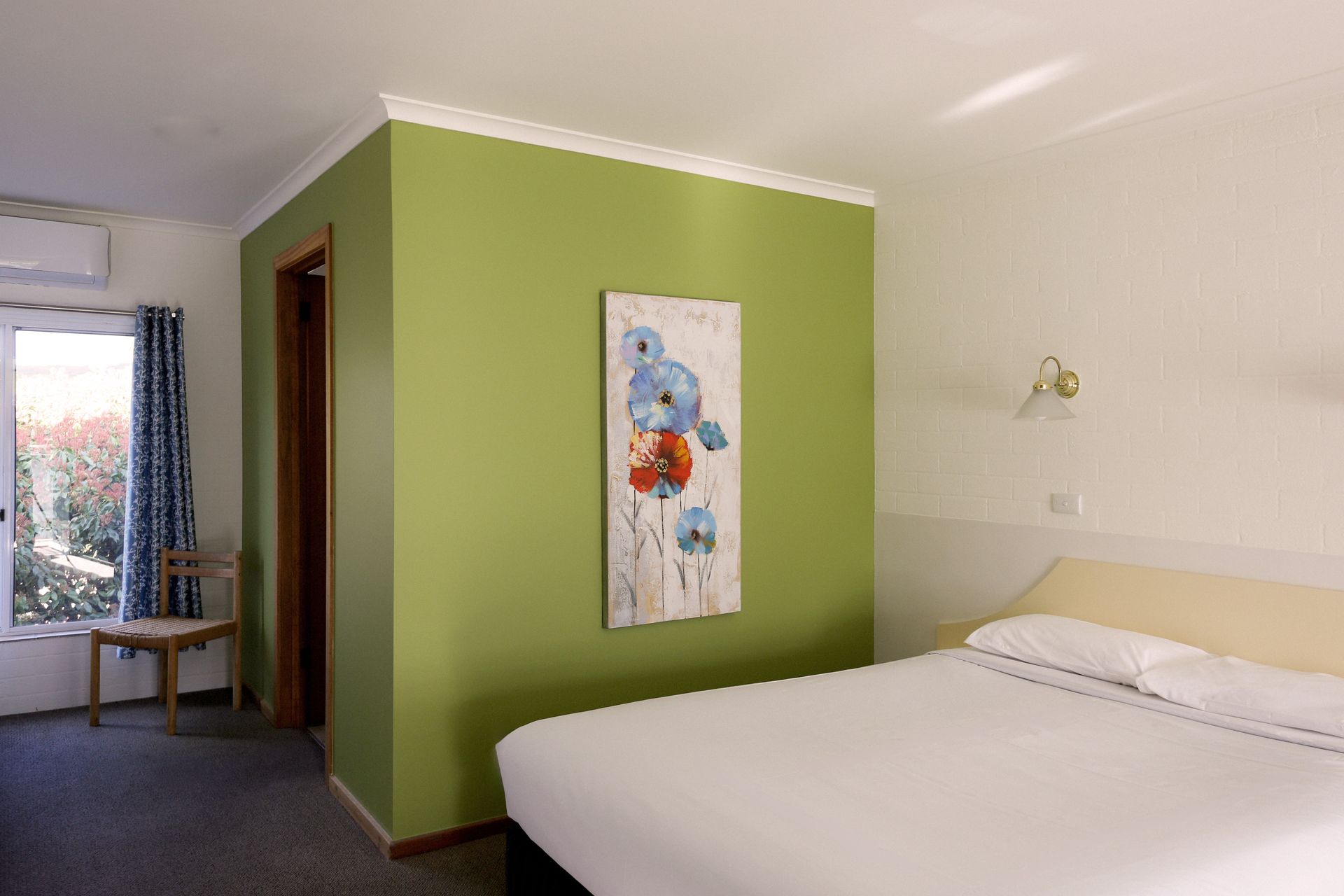 Bedroom with a green accent wall, double bed, artwork, and window.