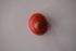 A red spinning top with a wooden handle on a white surface.