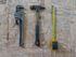 A hammer , wrench , and tape measure are sitting on a wooden table.