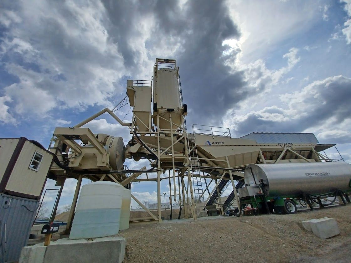 Three orange and white traffic cones are sitting on the side of a road.