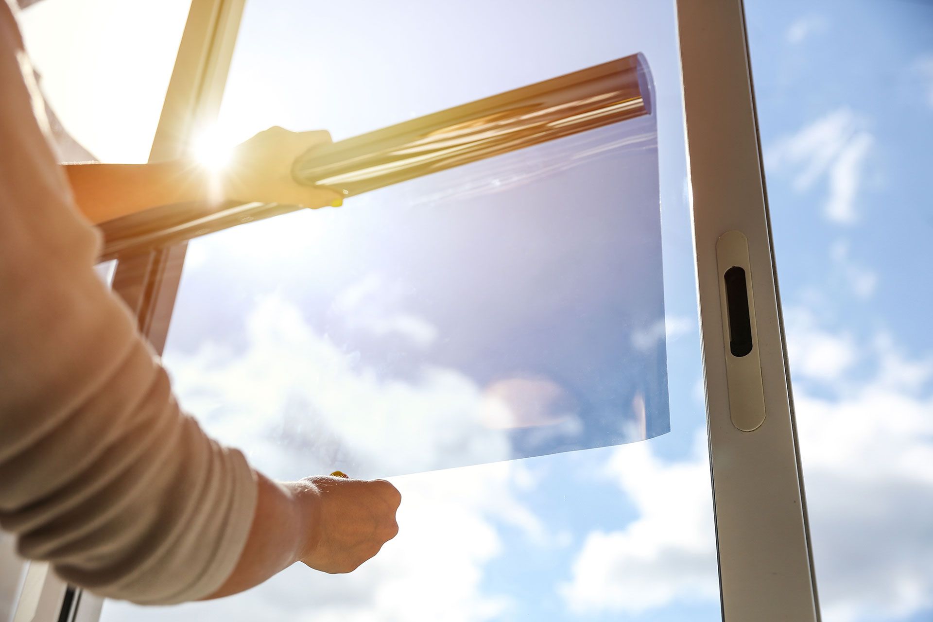tinted glass in the house. window dimming by dark film. hands apply tint film to the window. tint film on sky background. sky view through tinted glass
