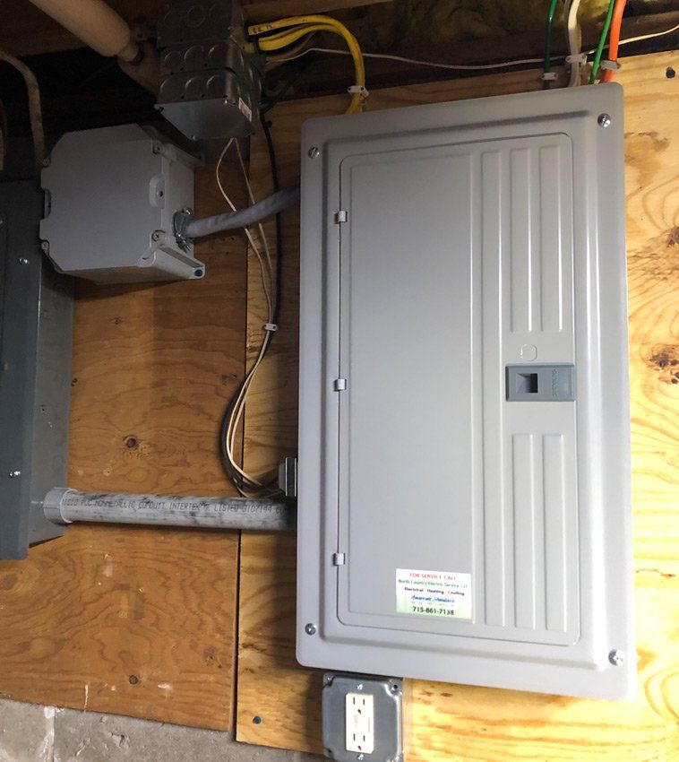 Electrical panel on a wooden wall with connected conduits, wiring, and an outlet.