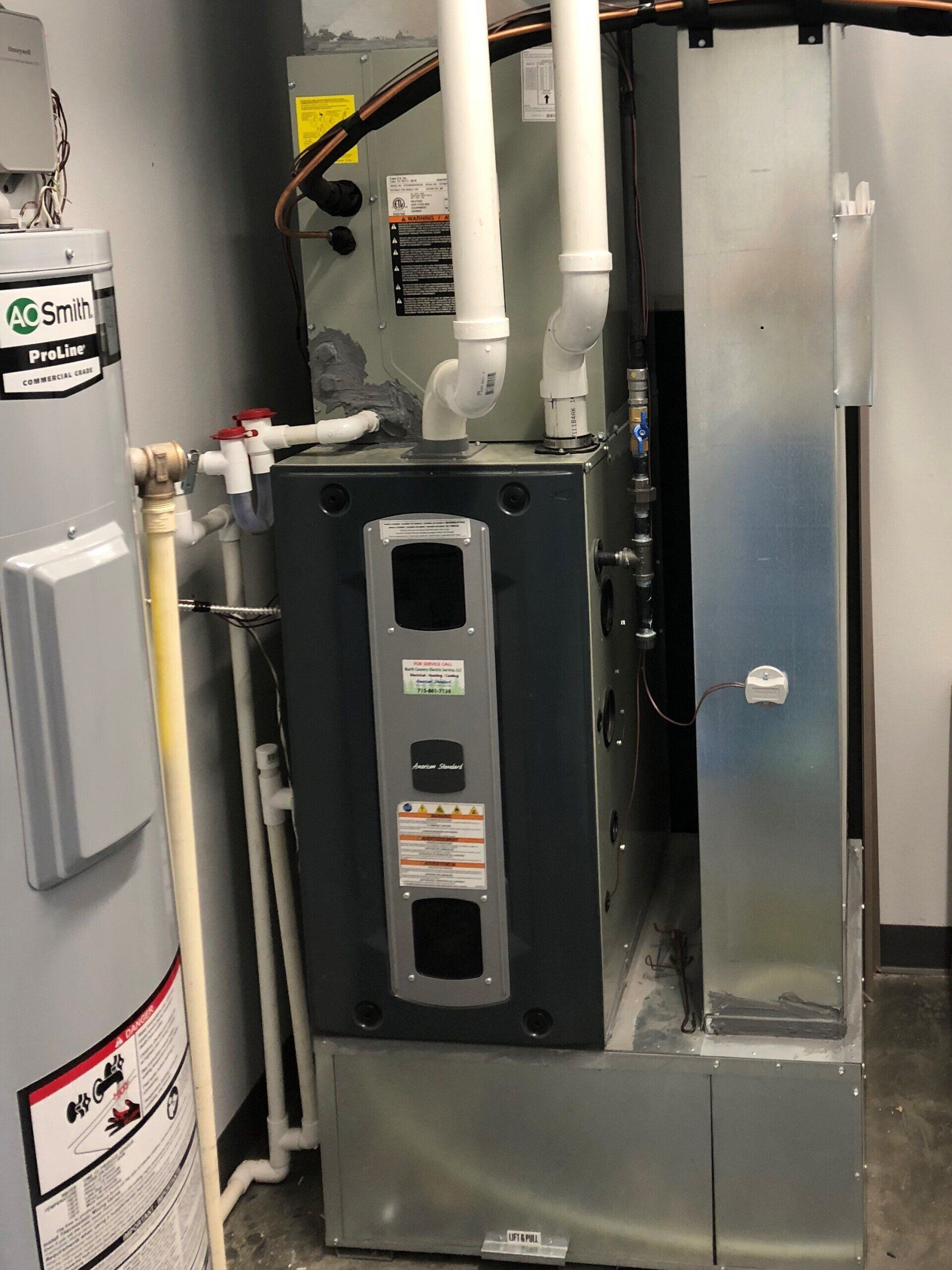 Furnace and water heater in an industrial setting, pipes and electrical components visible.