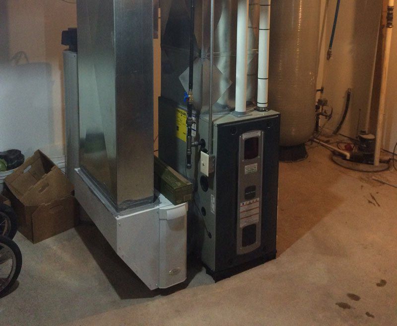 Furnace and ventilation system in a basement, against a wall.