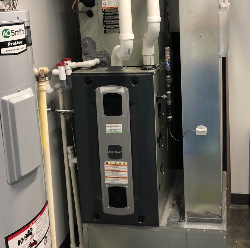 Water heater and furnace in an enclosed space. Gray, blue, and white appliances.