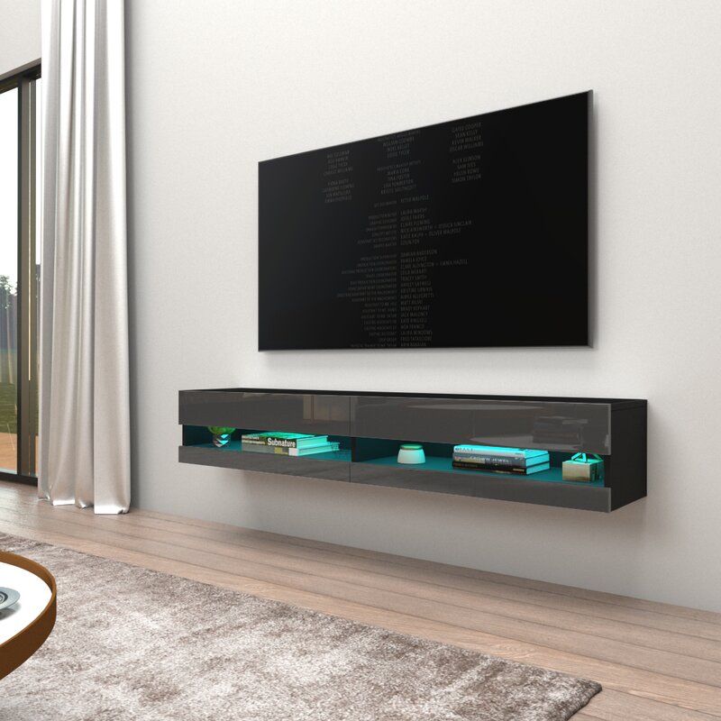 Wall-mounted dark gray TV cabinet with glowing blue lights under a mounted TV. Living room.