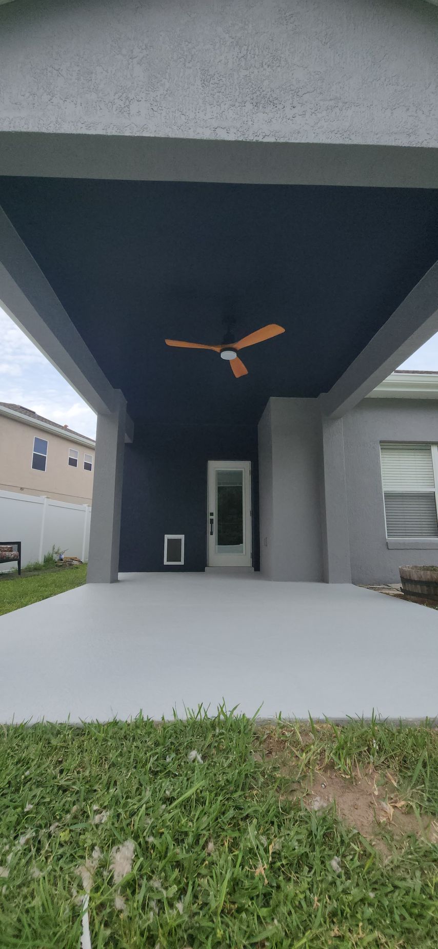 A ceiling fan is hanging from the ceiling of a covered patio.