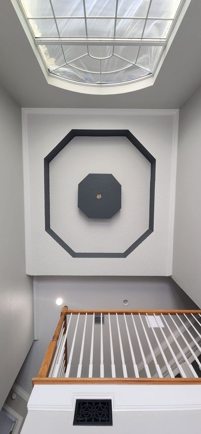 A staircase with a skylight and a clock on the ceiling.