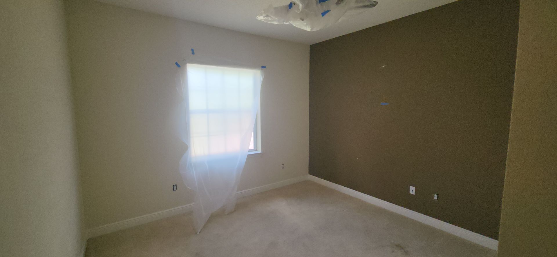 An empty bedroom with a window and a ceiling fan.