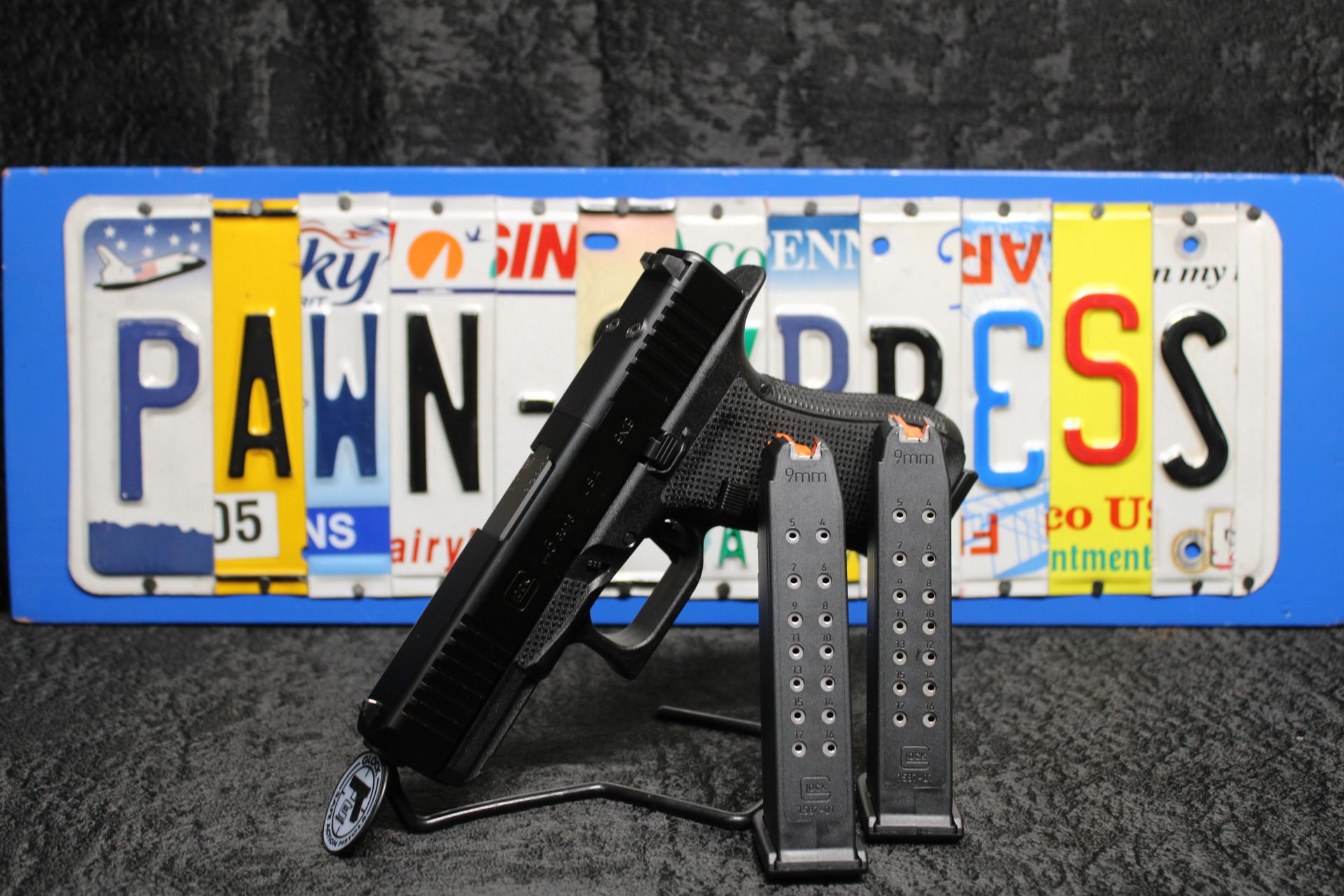 Handgun and two magazines in front of a Pennsylvania license plate with a black background