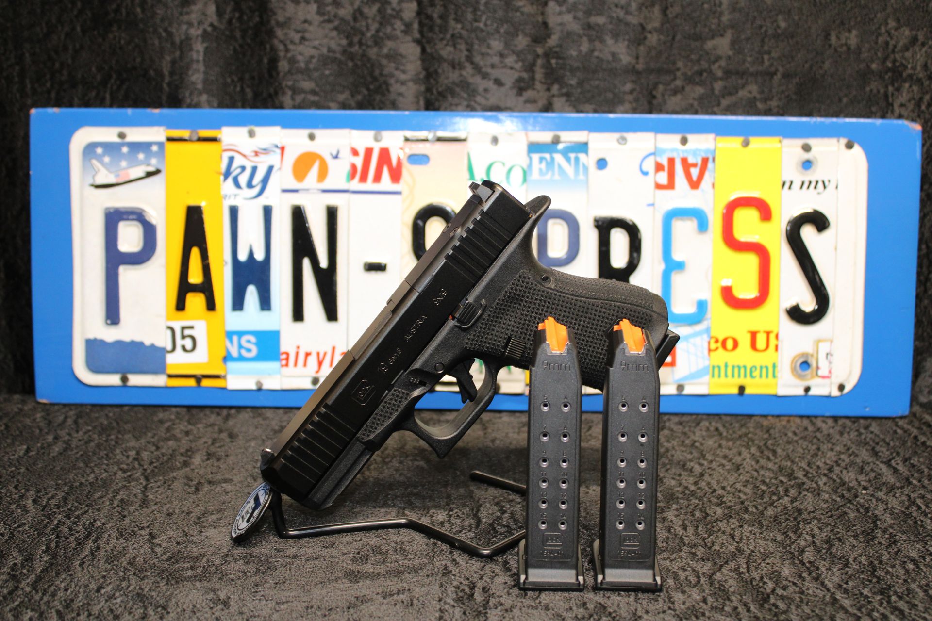 Black handgun with two magazines in front of a blue-and-white Pennsylvania license plate backdrop