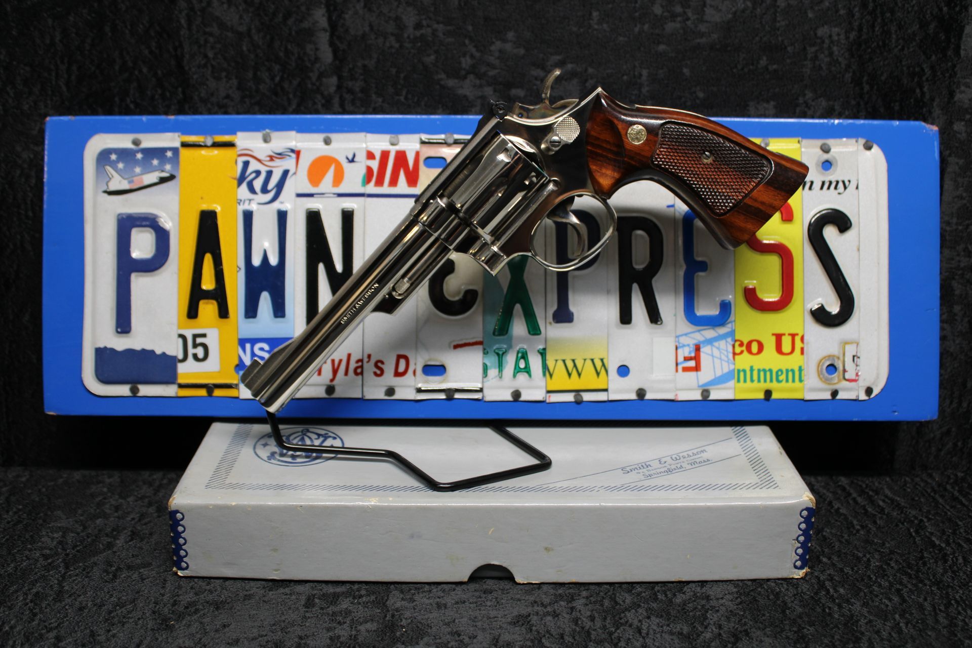 Pistol resting on a white box before a Pennsylvania license plate with “PAWN EXPRESS” text