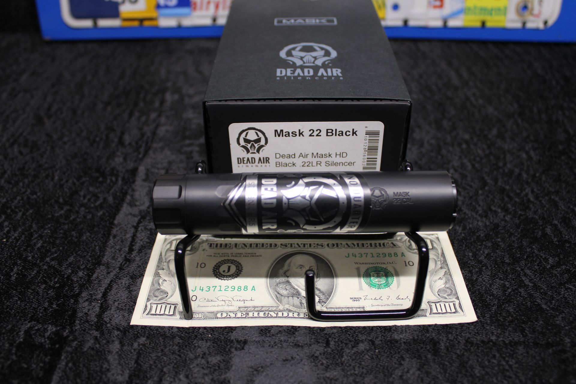 Black Mace 22 Black cylindrical device resting on a box, with a dollar bill and eyeglasses beneath it.