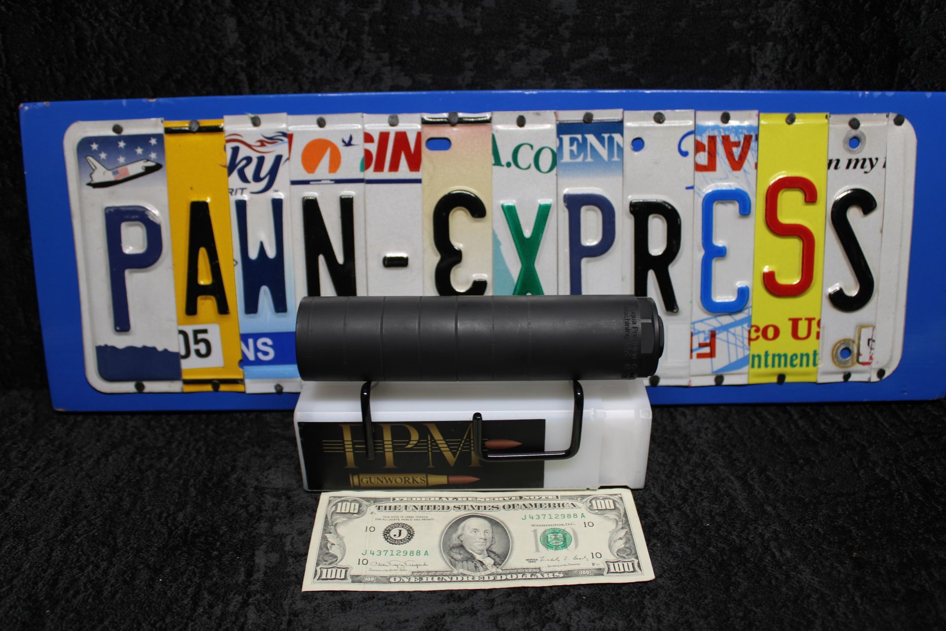 Pawn Express sign with a gavel and a one-dollar bill in front of a license plate backdrop