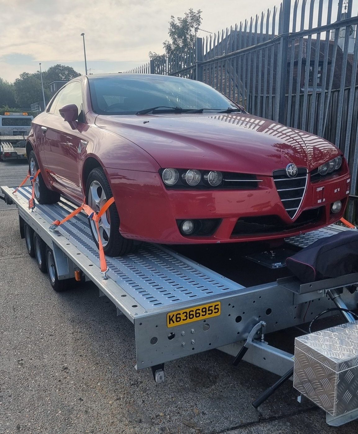 A red Alfa Romeo on a trailer towed by a Mercedes Sprinter, ready for transport  by MTC Transport