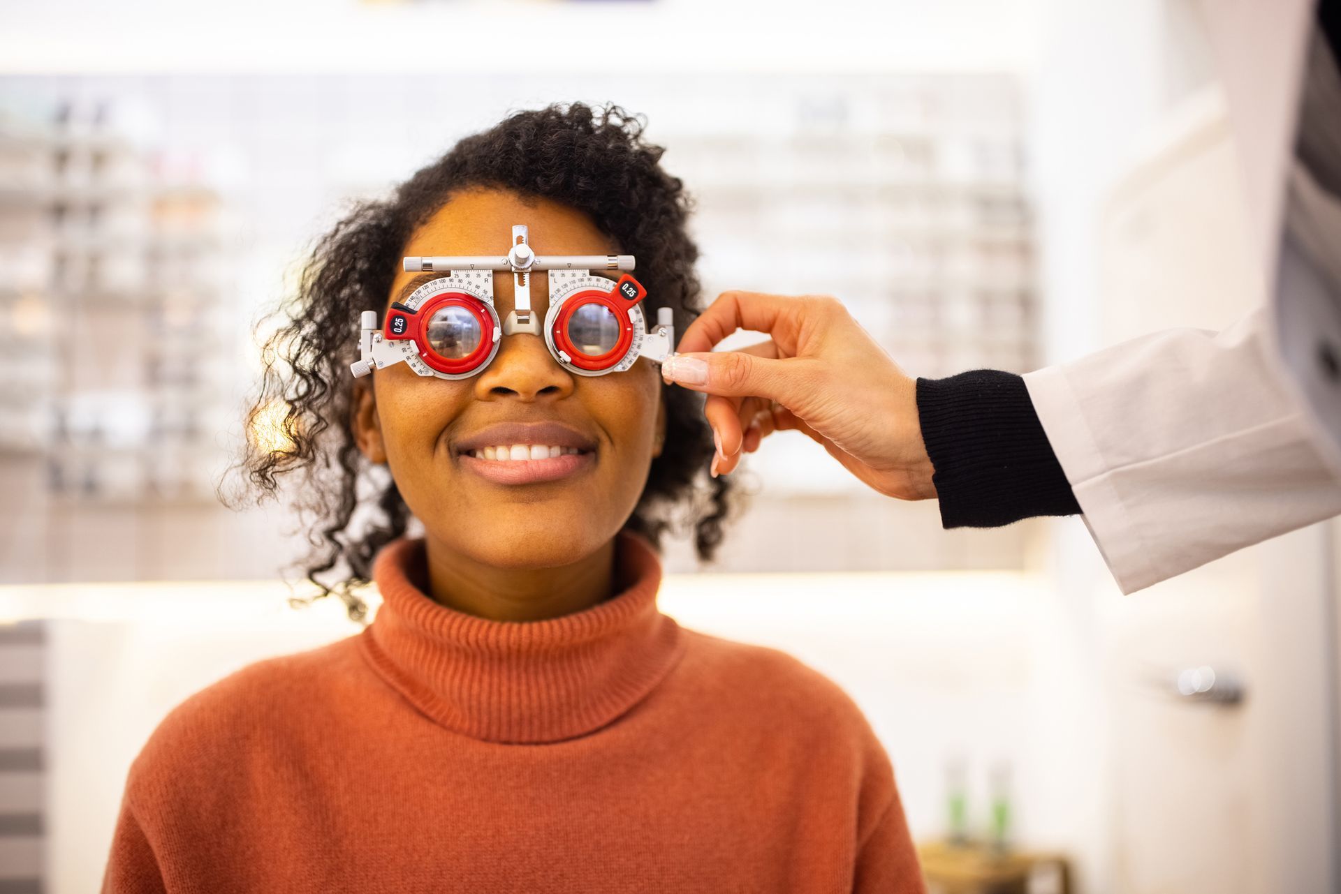 Person undergoing an eye exam. Doctor adjusts a trial frame on patient.