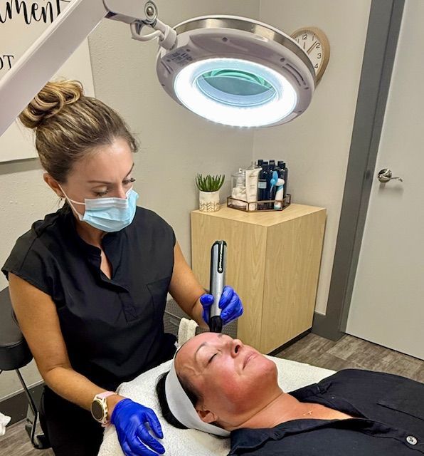 Close up of woman touching face with  a microneedling tool