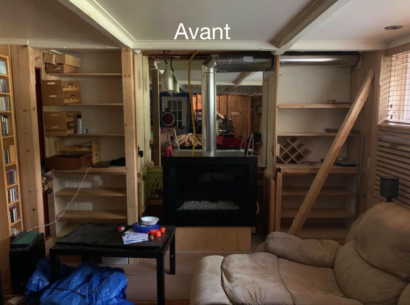 Un salon avec une cheminée et des escaliers et le mot avant au plafond