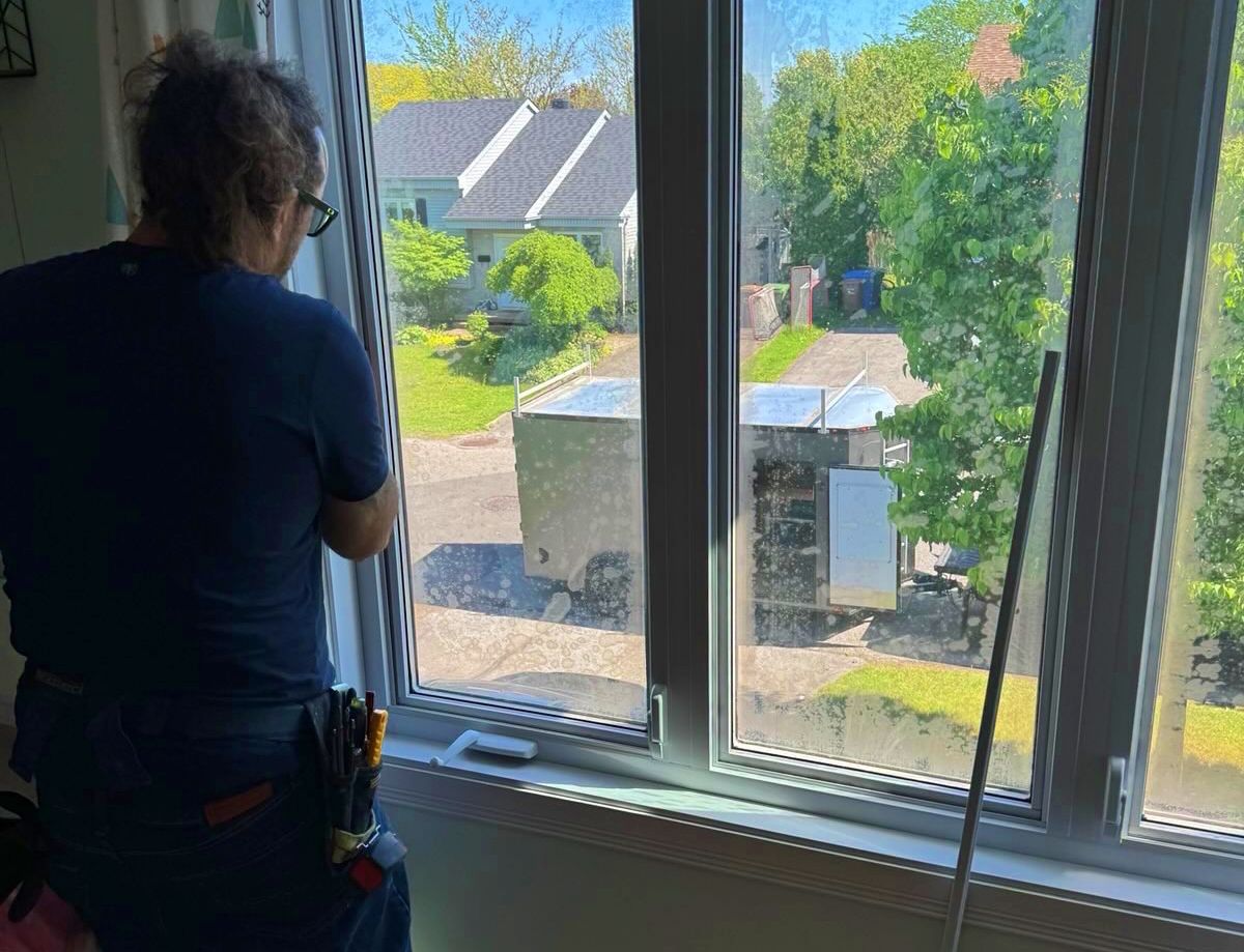 Un homme se tient devant une fenêtre et regarde dehors.