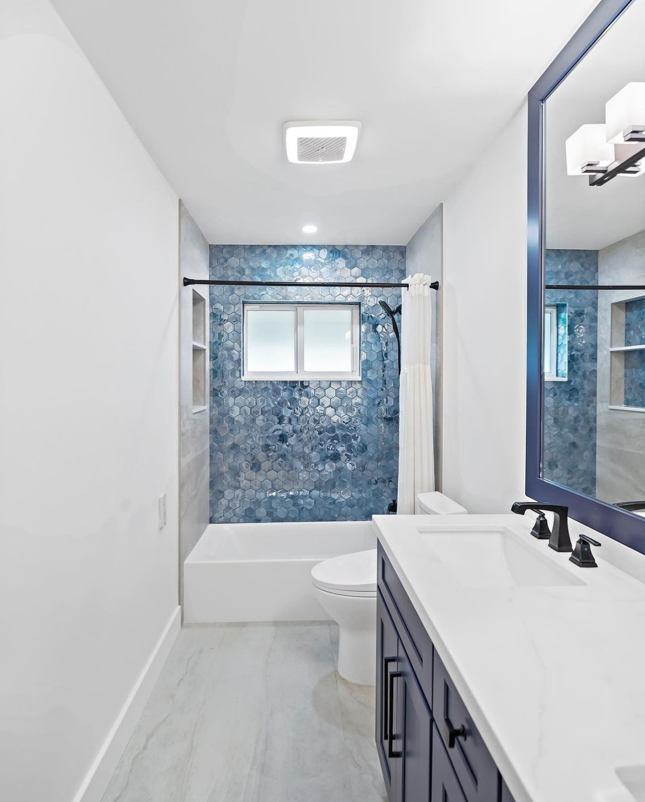 A bathroom with a toilet, sink, and mirror.