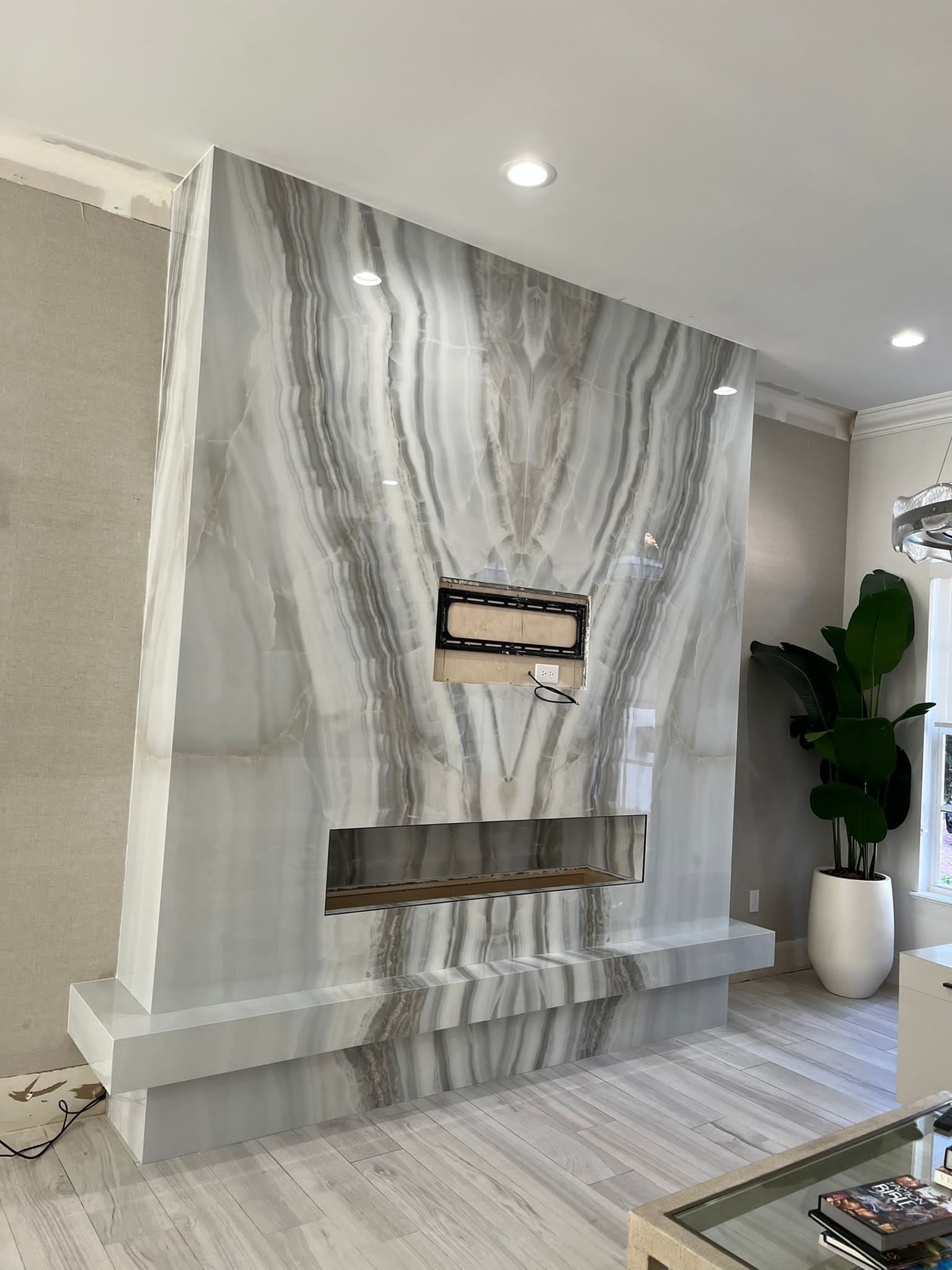 A living room with a fireplace and a marble wall.