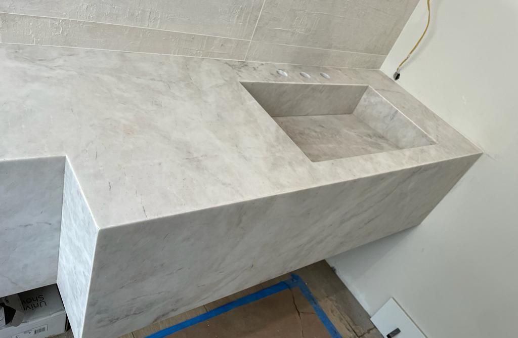 A white marble counter top with a sink in a bathroom.