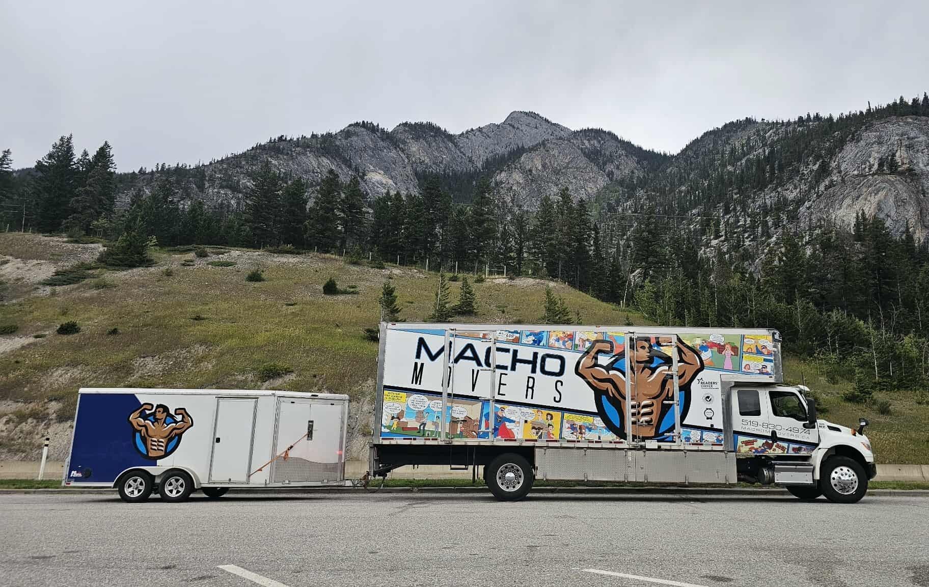 A Macho Movers truck and matching trailer parked against a scenic, mountainous backdrop.