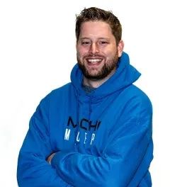 a man with a beard is wearing a blue hoodie and smiling .