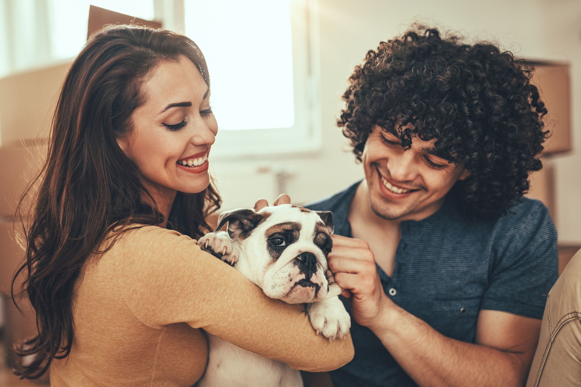 A man and a woman are sitting on a couch holding a dog.