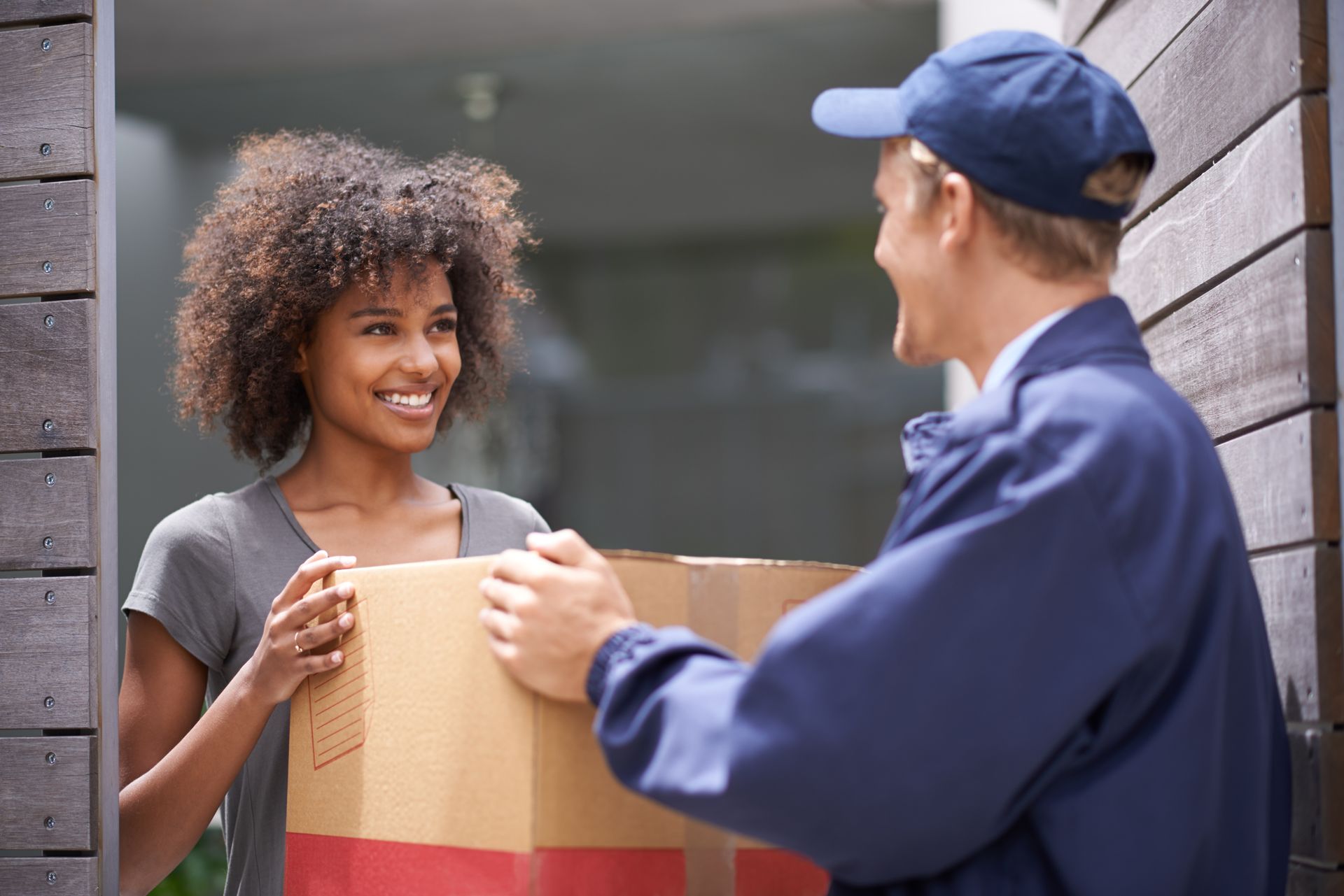 A woman is receiving a box from a delivery man.