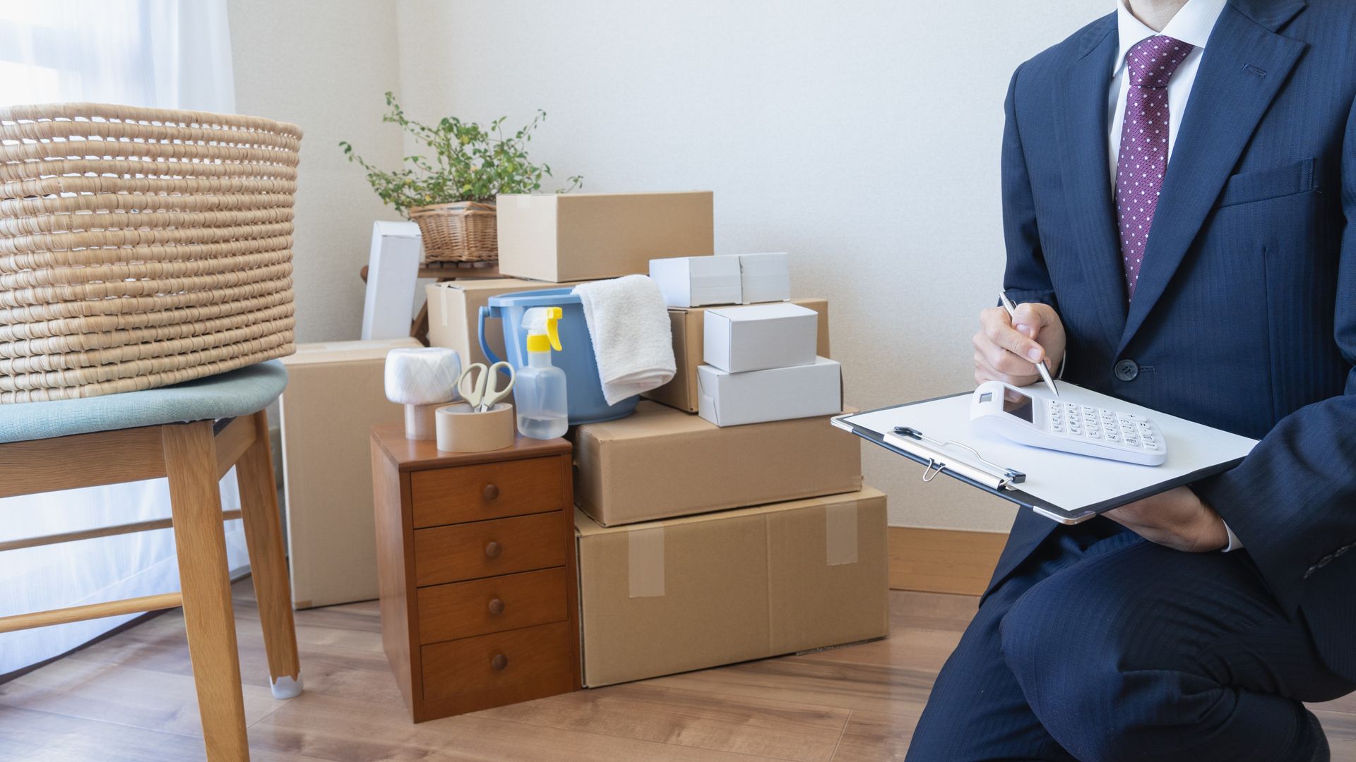 A man in a suit and tie is sitting on the floor in front of a pile of cardboard boxes.